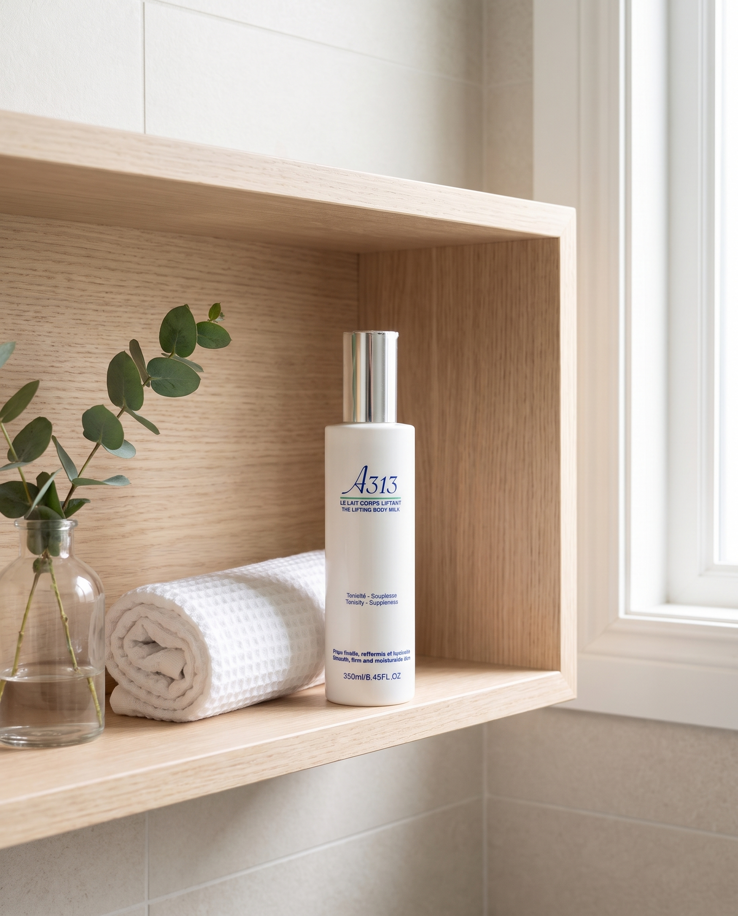 A313 Lifting Body Milk on a bathroom shelf with a rolled towel and eucalyptus sprig